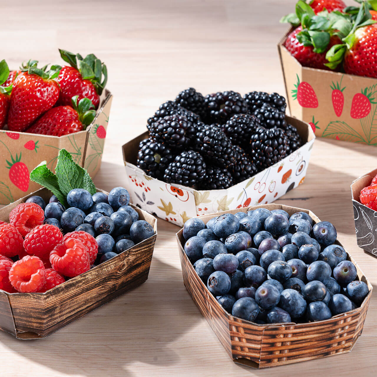 Obstschalen in unterschiedlichen Größen gefüllt mit Blaubeeren Himbeeren sowie Brombeeren sowie Schalen gefüllt mit Erdbeeren