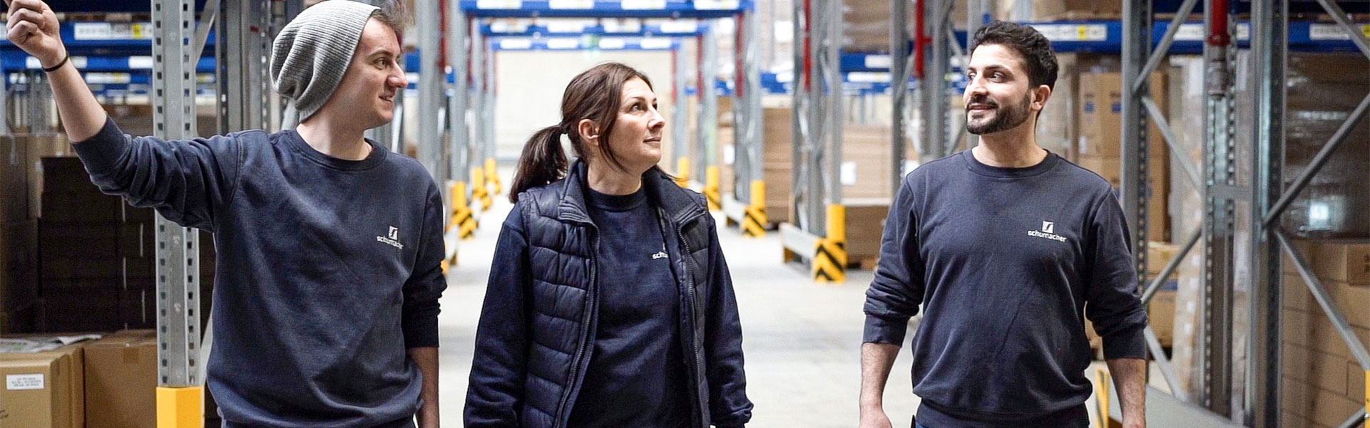 3 Logistik-Mitarbeiter laufen durch das Lager