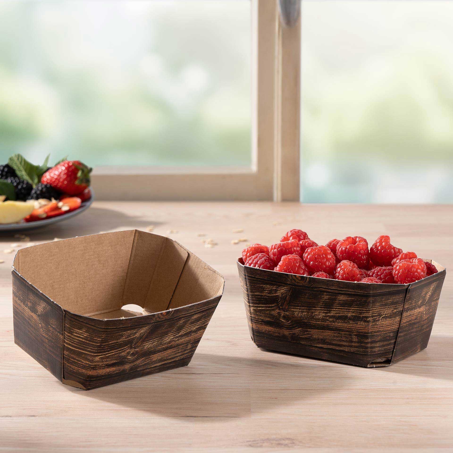 Zwei Beerenschalen 250g mit Himbeeren auf einem Tisch