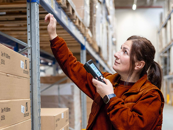 Person mit Scanner vor einem Regal