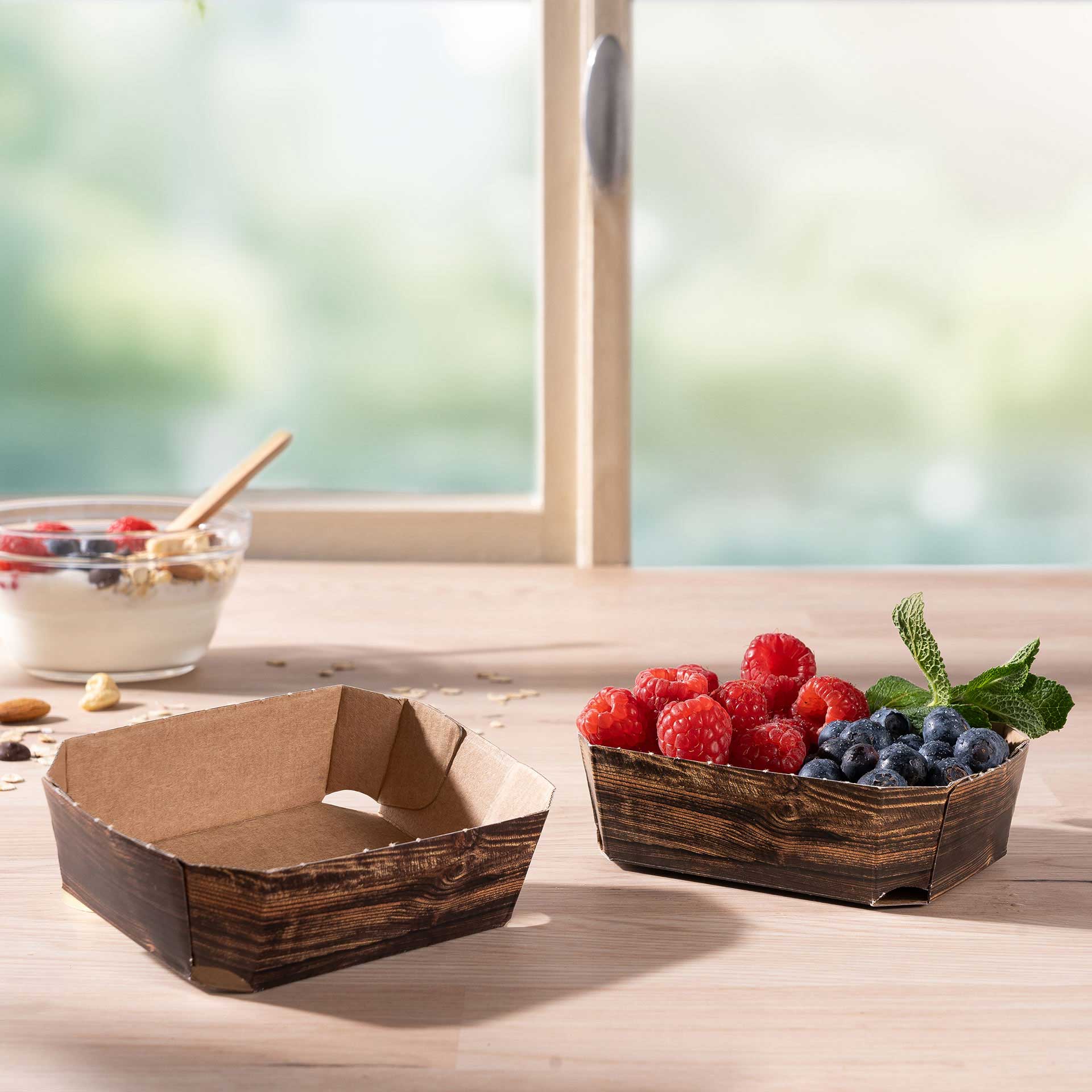 Zwei Beerenschalen aus Wellpappe 125g mit Himbeeren und Blaubeeren auf einem Tisch