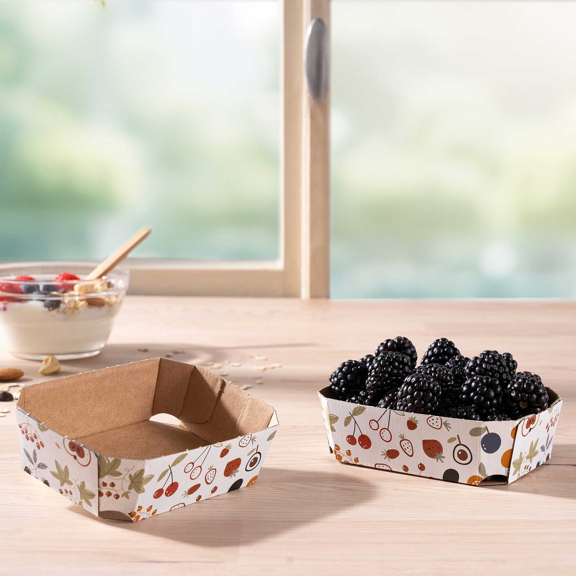 Zwei Beerenschalen aus Wellpappe 125g mit Brombeeren auf einem Tisch